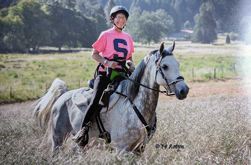 Young woman riding white Arabian horse